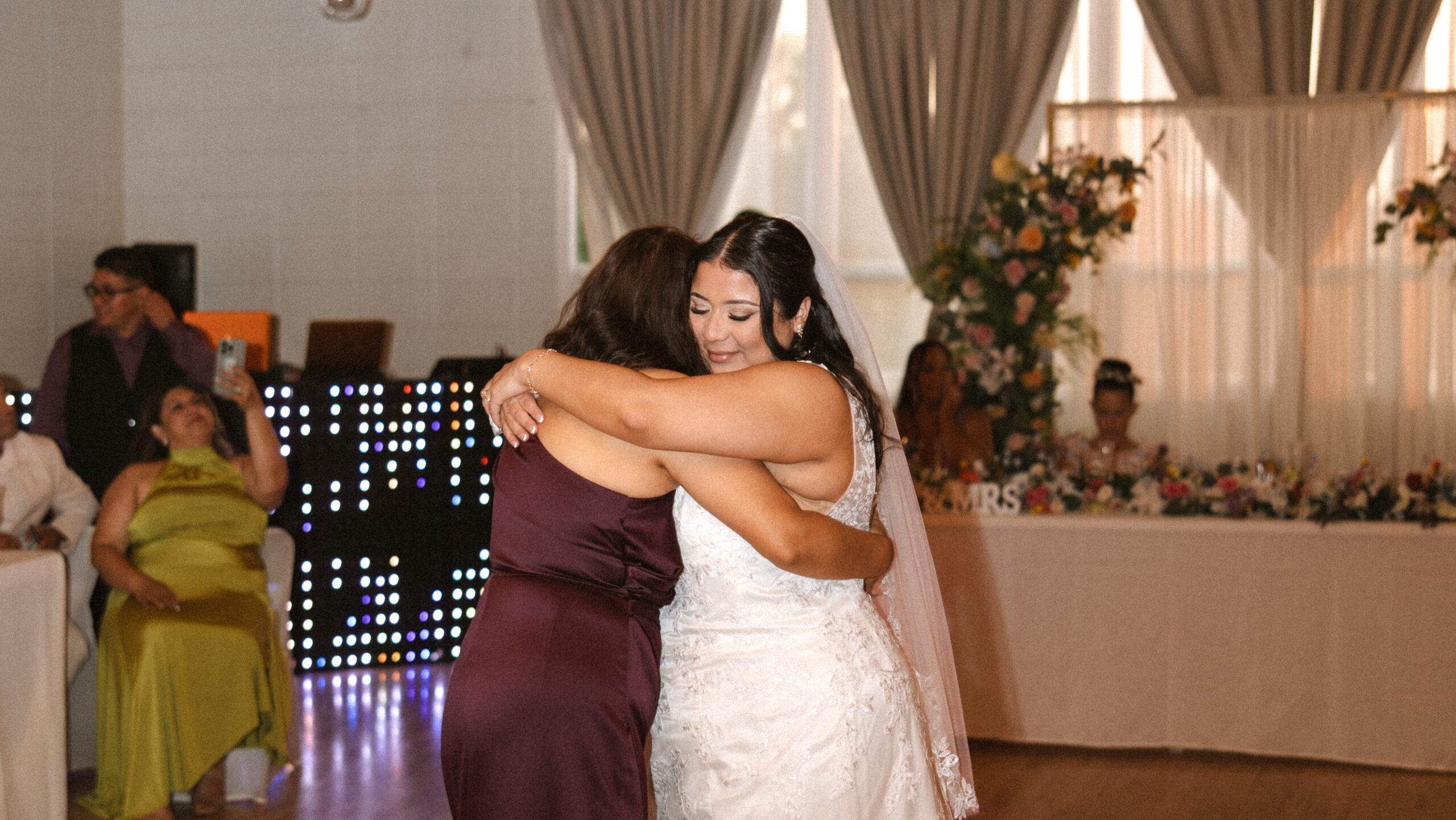 Bride sharing an emotional hug with her mother during indoor wedding reception in Washington
