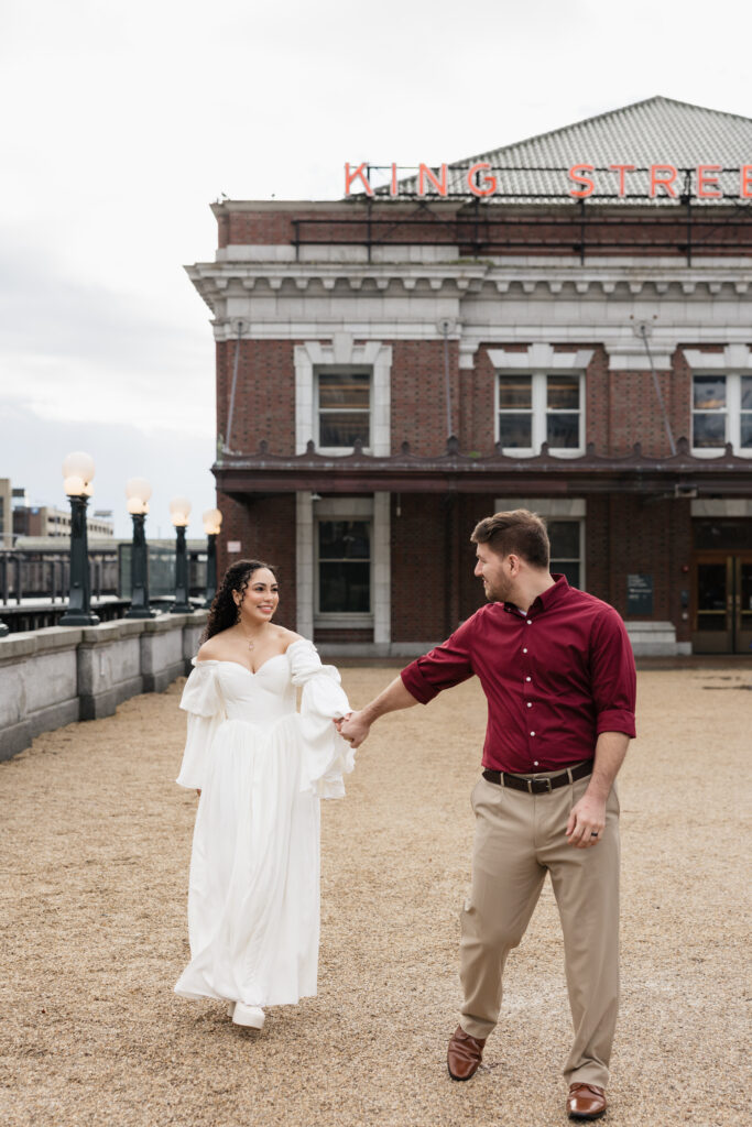 Bride and groom walking hand in hand in front of King Street Station in Seattle Washington
