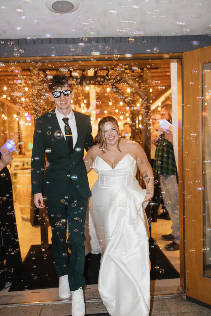 Bride and groom exiting wedding reception with bubbles at indoor Washington wedding
